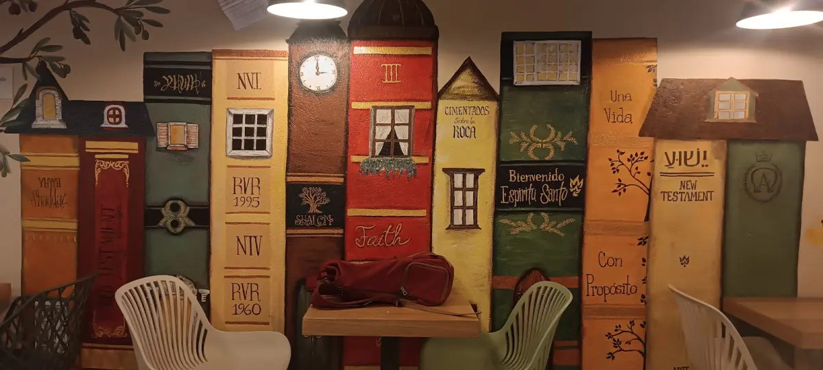 Salón de Olivo con mural de casitas de colores, mesas y sillas blancas